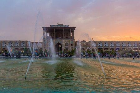 Foto de ISFAHAN, IRÁN - 10 DE JULIO DE 2019: Palacio Ali Qapu detrás de fuentes en la Plaza Naqsh-e Jahan en Isfahán, Irán - Imagen libre de derechos