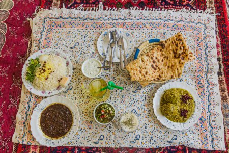 Foto de Traditional lunch in Iran. Bread, rice, Shirazi salad, Fesenjan and Kofte Sabzi. - Imagen libre de derechos