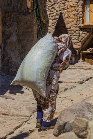 Photo for KANDOVAN, IRAN - JULY 15, 2019: Local woman carrying a sack in Kandovan village, Iran - Royalty Free Image