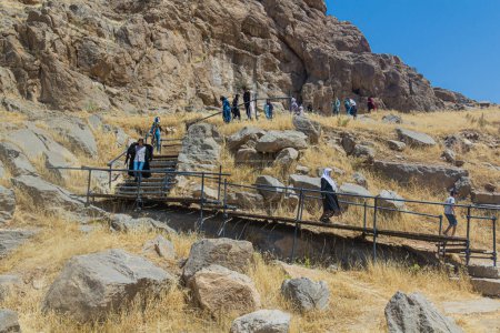 Foto de BISOTUN, IRAN - JULY 13, 2019: Visitors walking around archeological area in Bisotun, Iran - Imagen libre de derechos