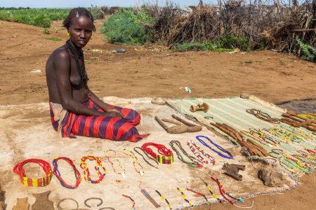 Photo for OMORATE, ETHIOPIA - FEBRUARY 5, 2020: Daasanach tribal girl selling souvenirs in her village near Omorate, Ethiopia - Royalty Free Image