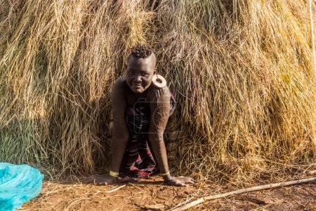Foto de OMO VALLEY, ETIOPÍA - 6 DE FEBRERO DE 2020: Muchacha de la tribu Mursi en su cabaña, Etiopía - Imagen libre de derechos