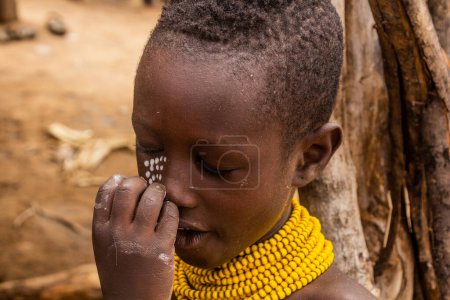 Téléchargez les photos : KORCHO, ÉTHIOPIE - 4 FÉVRIER 2020 : Garçon de la tribu Karo dans son village de Korcho se faisant peindre le visage, Éthiopie - en image libre de droit