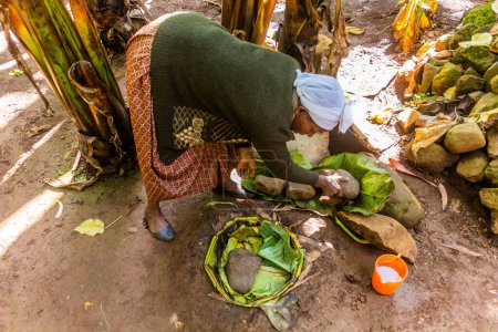 Foto de DORZE, ETIOPÍA - 30 DE ENERO DE 2020: Dorze woman está preparando pan kocho hecho de enset (plátano falso), importante fuente de alimentos, Etiopía - Imagen libre de derechos