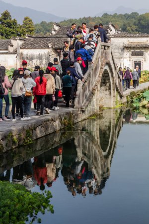 Photo for HONGCUN, CHINA - OCTOBER 29, 2019: People cross a bridge over South lake in Hongcun village, Anhui province, China - Royalty Free Image