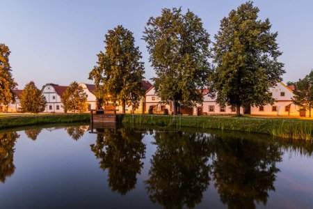 Photo for Pond and traditional houses of rural baroque style in Holasovice village, Czech Republic - Royalty Free Image