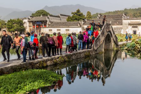 Téléchargez les photos : HONGCUN, CHINE - 29 OCTOBRE 2019 : Les gens traversent un pont au-dessus du lac Sud dans le village de Hongcun, province d'Anhui, Chine - en image libre de droit