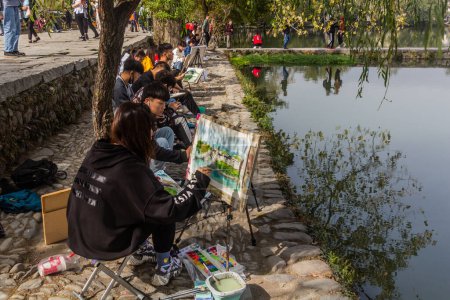 Photo for HONGCUN, CHINA - OCTOBER 29, 2019: Painters at the South lake in Hongcun village, Anhui province, China - Royalty Free Image