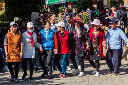 Foto de LIJIANG, CHINA - 8 DE NOVIEMBRE DE 2019: La gente local baila en el casco antiguo de Lijiang, provincia de Yunnan, China - Imagen libre de derechos