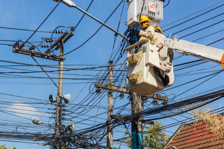 Photo for CHIANG MAI, THAILAND - DECEMBER 6, 2019: Electricians fixing cables in a mess of wires in Chiang Mai, Thailand - Royalty Free Image