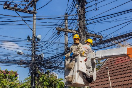 Téléchargez les photos : CHIANG MAI, THAÏLANDE - 6 DÉCEMBRE 2019 : Des électriciens réparent des câbles dans un désordre de fils à Chiang Mai, Thaïlande - en image libre de droit