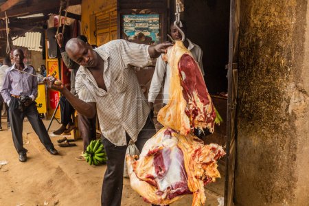 Foto de BUDADIRI, UGANDA - 25 DE FEBRERO DE 2020: Carnicero local cortando carne en la aldea de Budadiri, Uganda - Imagen libre de derechos