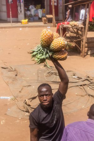 Photo for UGANDA - MARCH 7, 2020: Pineapple vendor selling his fruit to bus passengers, Uganda - Royalty Free Image