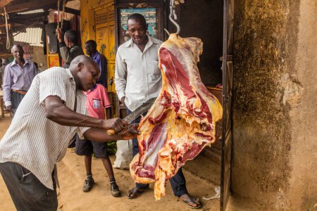 Foto de BUDADIRI, UGANDA - 25 DE FEBRERO DE 2020: Carnicero local cortando carne en la aldea de Budadiri, Uganda - Imagen libre de derechos