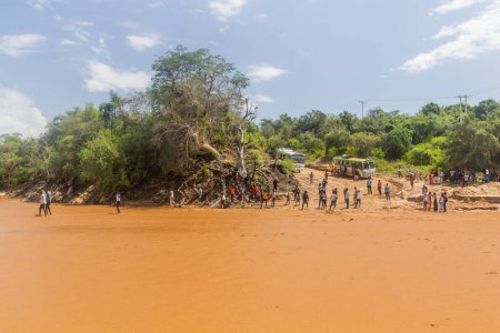 Foto de OMO VALLEY, ETIOPÍA - 4 DE FEBRERO DE 2020: Personas cruzando el río Kizo, Etiopía - Imagen libre de derechos