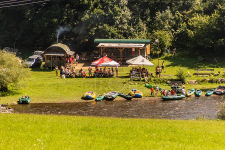 Photo for VLTAVA, CZECHIA - AUGUST 7, 2020: Tourists enjoy a stop for a refreshment during canoeing at Vltava river near Cesky Krumlov, Czech Republic - Royalty Free Image