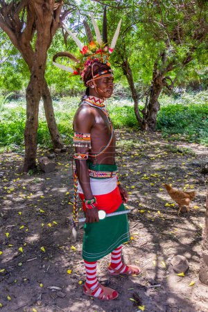 Foto de SUR HORR, KENIA - 12 DE FEBRERO DE 2020: Joven de la tribu Samburu con un colorido casco hecho de plumas de avestruz después de su ceremonia de circuncisión. Tomado en la aldea de South Horr, Kenia - Imagen libre de derechos
