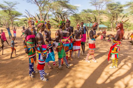 Photo for SOUTH HORR, KENYA - FEBRUARY 12, 2020: Group of Samburu tribe young men dancing wearing colorful headpieces made of ostrich feathers after their circumcision ceremony. - Royalty Free Image
