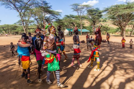 Photo for SOUTH HORR, KENYA - FEBRUARY 12, 2020: Group of Samburu tribe young men and women dancing wearing colorful headpieces made of ostrich feathers after malecircumcision ceremony. - Royalty Free Image