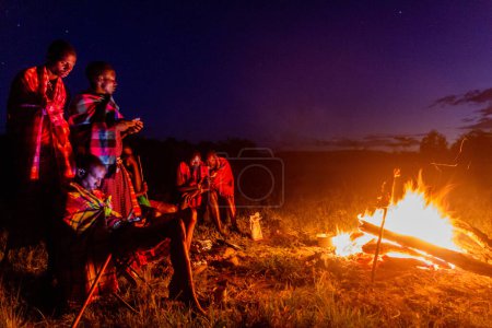Téléchargez les photos : MASAI MARA, KENYA - 20 FÉVRIER 2020 : Masai men with a bonfire, Kenya - en image libre de droit