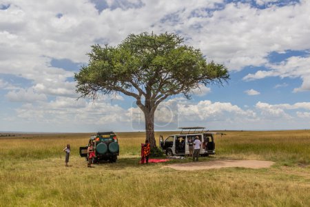 Photo for MASAI MARA, KENYA - FEBRUARY 19, 2020: Safari vehicles under a tree in Masai Mara National Reserve, Kenya - Royalty Free Image