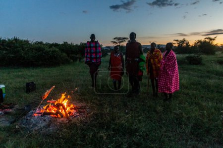 Photo for MASAI MARA, KENYA - FEBRUARY 20, 2020: Masai men performing their Jumping Dance next to a bonfire, Kenya - Royalty Free Image