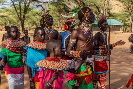Photo for SOUTH HORR, KENYA - FEBRUARY 12, 2020: Group of Samburu tribe young men and women dancing wearing colorful headpieces made of ostrich feathers after malecircumcision ceremony. - Royalty Free Image