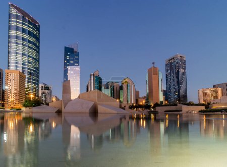 Foto de ABU DHABI, Emiratos Árabes Unidos - 19 de octubre de 2021: Vista nocturna de los rascacielos y la mezquita Musalla Al Hosn en el centro de Abu Dhabi, Emiratos Árabes Unidos. - Imagen libre de derechos