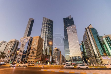 Foto de ABU DHABI, Emiratos Árabes Unidos - 19 de octubre de 2021: Vista nocturna de rascacielos en el centro de Abu Dhabi, Emiratos Árabes Unidos. - Imagen libre de derechos