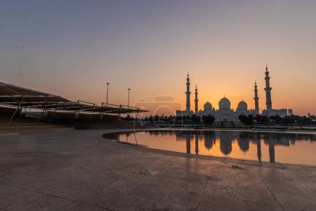 Foto de Puesta de sol detrás de la Gran Mezquita Sheikh Zayed en Abu Dhabi, Emiratos Árabes Unidos. - Imagen libre de derechos