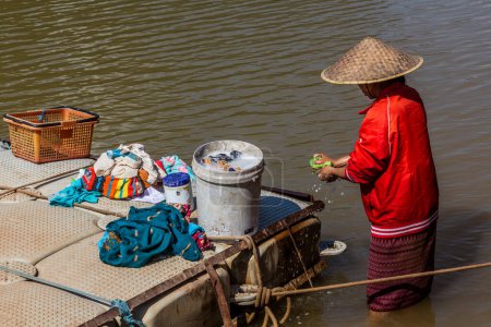 Foto de MUANG NGOI NEUA, LAOS - 25 de noviembre de 2019: Mujer local lavando ropa en el río Nam Ou en el pueblo de Muang Ngoi Neua, Laos - Imagen libre de derechos