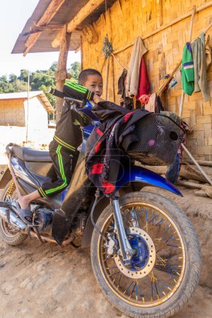 Photo for LUANG NAMTHA, LAOS - NOVEMBER 16, 2019: Child on a motorbike in a village near Luang Namtha, Laos - Royalty Free Image