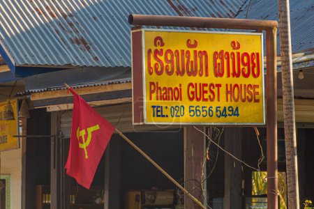 Téléchargez les photos : NONG KHIAW, LAOS - 26 NOVEMBRE 2019 : Signer Phanoi Guest House et un drapeau marteau et faucille à Nong Khiaw, Laos - en image libre de droit