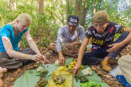 Téléchargez les photos : NAM HA, LAOS - 15 NOVEMBRE 2019 : Guides locaux et touristes mangeant dans la forêt de l'aire nationale protégée de Nam Ha, Laos - en image libre de droit