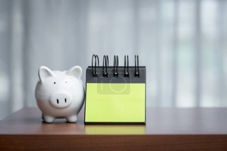 Piggy bank and notepad on a wooden table with copy space, embodying the concept of combining financial mindfulness with thoughtful planning and the potential for recording ideas or goals.