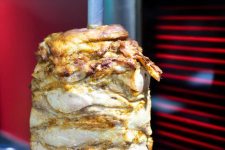 Téléchargez les photos : Viande de poulet brochée rotative grillée dans un gril en acier inoxydable et prête à servir dans un sandwich typique au kebab de restauration rapide du Moyen-Orient - en image libre de droit