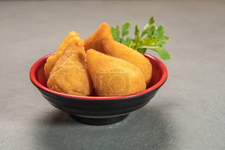 traditional fried coxinha in plate on slate background, popular brazilian snack served at parties