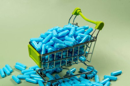 blue medicine capsule in miniature shopping cart to symbolize medicine purchase