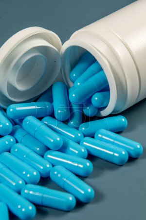 Gelatine-Pillen ragen aus einer weißen Medikamentenflasche. Pharmazeutische Produktion. Globale Gesundheit. Antibiotikaresistenz, Pharmaindustrie.