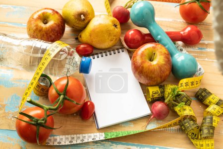 bloc-notes en papier avec des fruits et du matériel de gymnastique associés à l'alimentation et la perte de poids