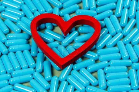 Photo for Heart shape and blue capsules. Importance of treatment for problems - Royalty Free Image