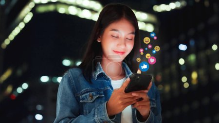 Photo for Young asian women watching live streaming video in the night city. Happy female using mobile smartphone social media application - Royalty Free Image