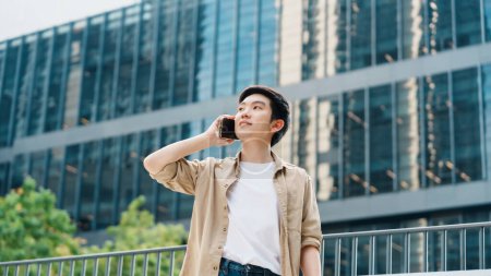 Photo for Portrait of handsome Asian student using smartphone. A young man standing outdoor happy smiling with holding mobile phone - Royalty Free Image
