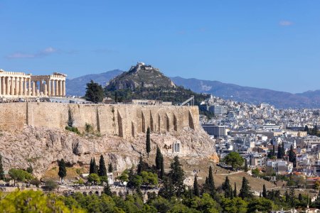 Foto de Atenas, Grecia - 17 de octubre de 2022: Vista de la Acrópolis de Atenas sobre un fondo de cielo azul desde Muse Hill. Vista aérea de la ciudad en la distancia y el Monte Lycabettus - Imagen libre de derechos