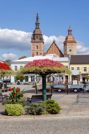 Photo for Nowy Sacz, Poland - August 30, 2022: View of the Market Square on a sunny day with decorative colorful flower arrangements. In the background the towers of the Collegiate Basilica of St. Malgorzata - Royalty Free Image
