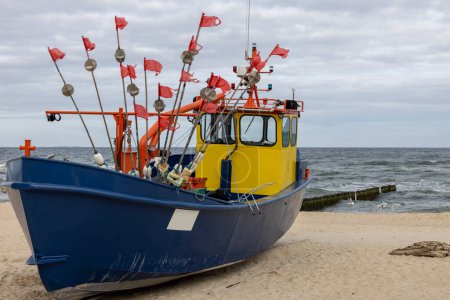 Barco de pesca en la playa de arena en el Mar Báltico en un día soleado, Isla Wolin, Miedzyzdroje, Polonia.
