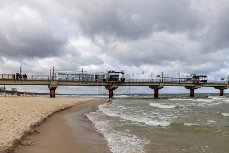 Photo for Miedzyzdroje, Poland - September 15, 2022: Miedzyzdroje pier, long wooden jetty entering the Baltic Sea from the beach, beautiful seaside landscape. Cloudy sky and windy weather, Empty beach because of off season - Royalty Free Image