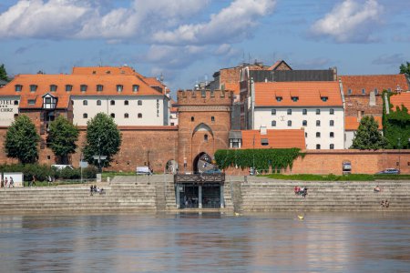 Téléchargez les photos : Torun, Pologne - 26 juin 2020 : Vue sur la Vistule depuis la plate-forme d'observation de la vieille ville sur l'autre rive du fleuve. Porte du pont, l'une des trois portes de la ville médiévale - en image libre de droit
