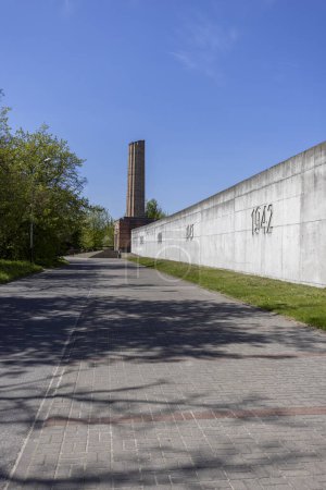 Foto de Lodz, Polonia - 4 de mayo de 2023: Estación de tren de Radegast, lugar de deportación de judíos a campos de concentración nazis alemanes. Alley of Remembrance of the Victims of the Lodz Ghetto. Chimenea simbólica de crematorio - Imagen libre de derechos