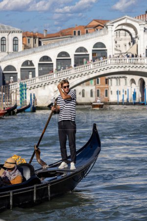 Téléchargez les photos : Venise, Italie - 27 septembre 2023 : Vue sur le pont du Rialto (Ponte de Rialto) sur le Grand Canal et la télécabine avec touriste sur l'eau. C'est le plus ancien des quatre ponts de la ville. - en image libre de droit